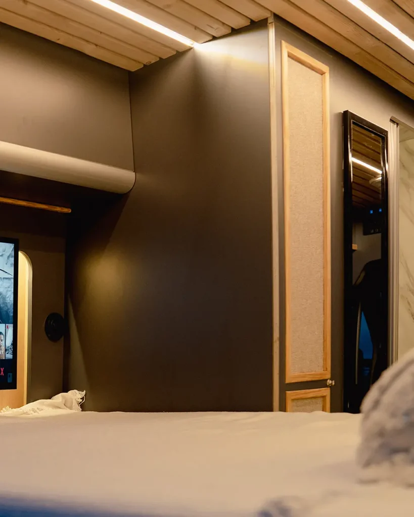 Vista interior del área de descanso en la Fiat Ducato, destacando un diseño elegante y moderno con paredes y techos en tonos oscuros y madera.