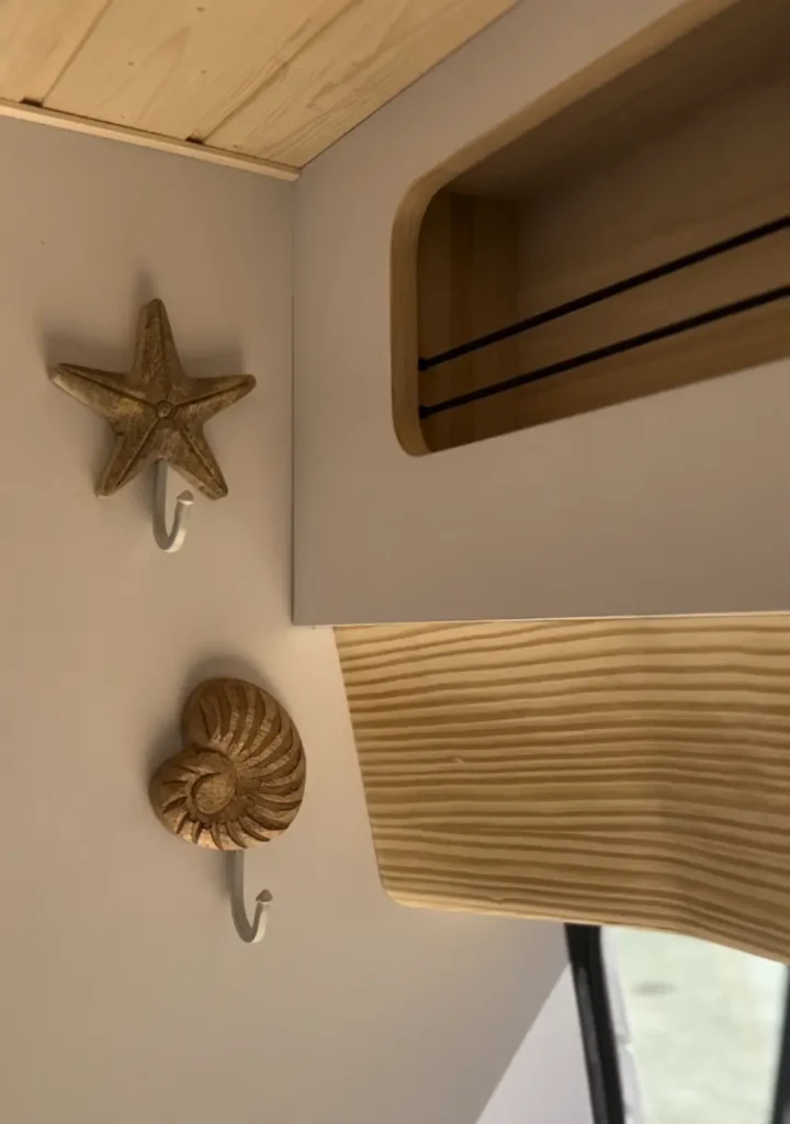 Decoración interior de una furgoneta camperizada con un gancho en forma de estrella de mar, complementando el tema náutico del vehículo.