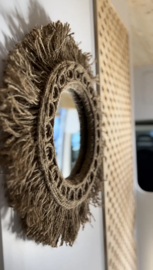 Decoración rústica en una furgoneta Fiat Ducato, mostrando un espejo redondo con marco de cuerda, añadiendo un toque cálido y personal al interior.